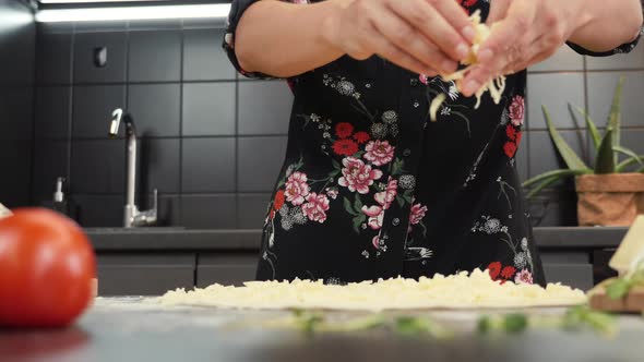 Grated mozzarella cheese falling on pizza base, close up