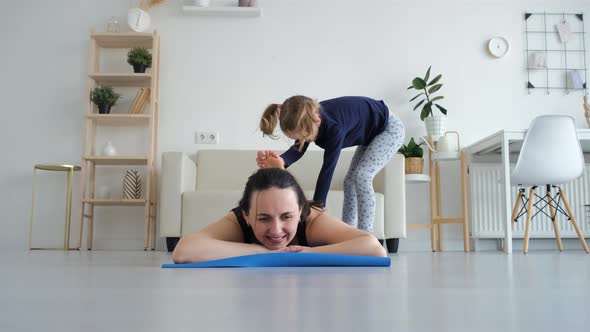 Little Girl Helping Mom Stretching Legs at Home