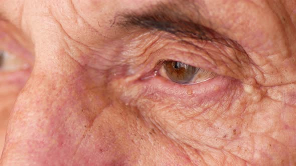 sad wrinkled eyes of a Caucasian elderly man over 70 looking into the distance