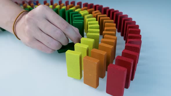 Line up of Dominoes in Rainbow Falling Colors with LGBT Colors of a Hand