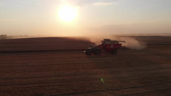 Aerial shot: combine pouring harvested wheat into tractor tipper