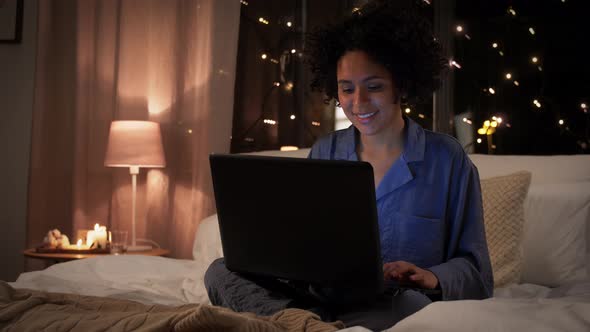 Woman with Laptop in Bed at Home at Night