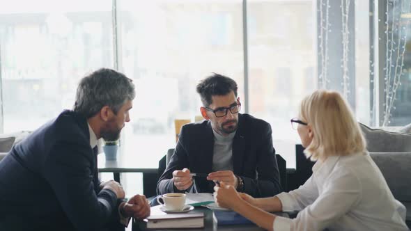 Male and Female Entrepreneurs Discussing Agreement During Meeting in Cafe