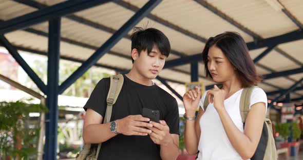 Couple checks location on smartphone online map at train station