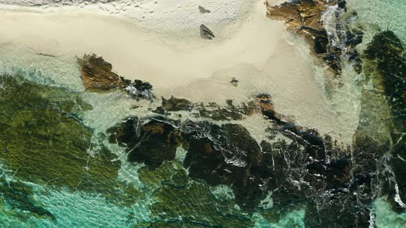 Perfect white sandy beach from above with gentle waves, tropical island, aerial