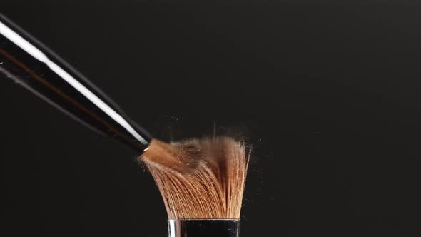 Two Makeup Brushes Touch Each Other on Black Background and Small Particles of Cosmetics - Shadows