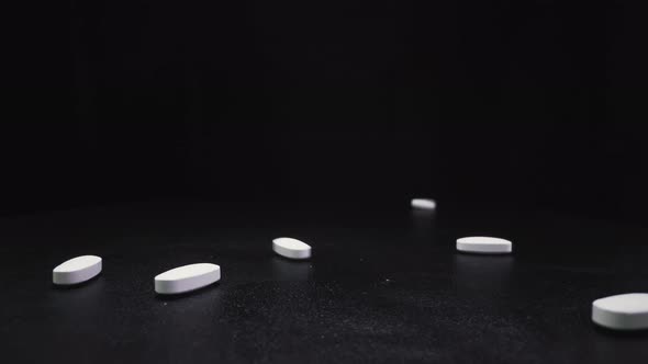 Throwing Numerous Pills Onto Black Surface Close View