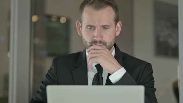 Close Up of Businessman Thinking and Working on Laptop at Night