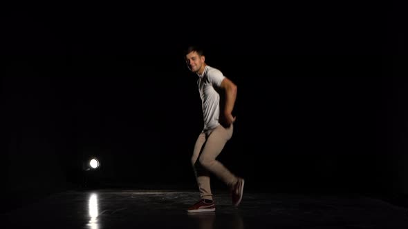 Young Man Dancing Breakdance in Black Studio
