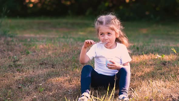 Young Funny Blond Lady Sits in Green Tree Shadow on Meadow