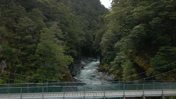 Aerial view of metal bridge crossing deep narrow river in Blue Pools in New Zealand