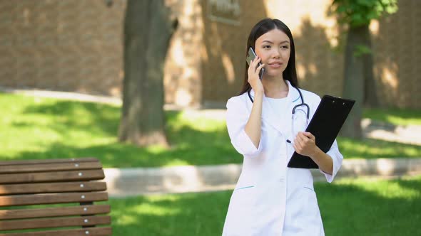 Smiling Nurse Talking Phone With Patient in Hospital Park, Medical Care, Health