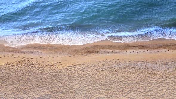 View of the sea waves on the beach. Yellow sand and blue water