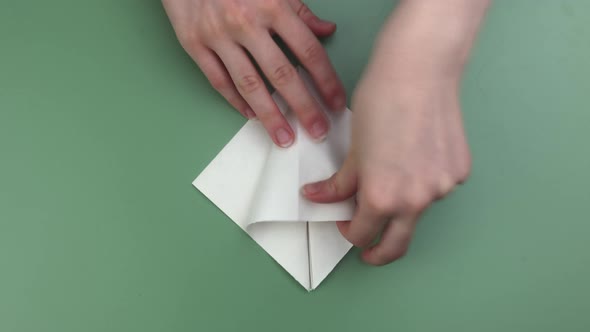 Hands folding origami on the green background speeded video