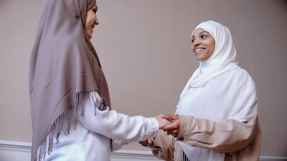 Two Young Muslim Girls Talk to Each Other Holding Hands and Smiling