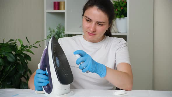 The Housewife Sprays a Special Solution on the Dirty Sole of the Iron