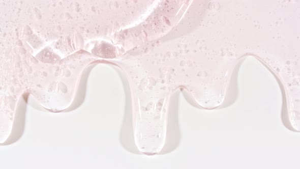 Pink Transparent Cosmetic Gel Fluid With Molecule Bubbles Flowing On The Plain White Surface