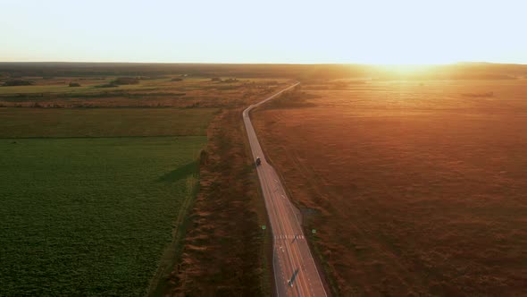 Aerial View of a Car Driving at Sunset in the Countryside in Summer