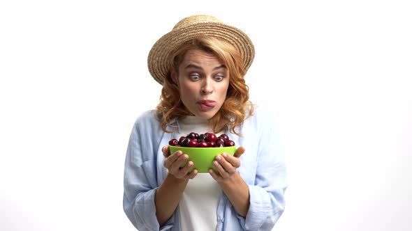 Hungry Girl Farmer in Straw Summer Hat Licking Lips and Eat Cherry with Hunger Yummy