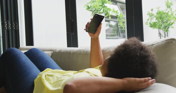 Video of plus size african american woman relaxing on sofa with smartphone
