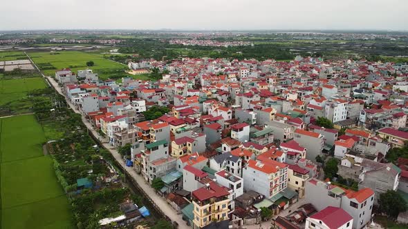 Areal View of a Suburban Town with Modern Houses and Green Paddy Fields.