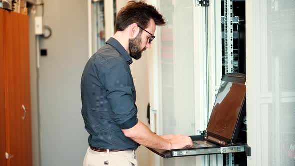 IT Technician Works With Ware And Cables in Big Data Center. Connecting Lan Cable To Mainframe.