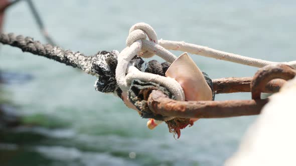 An old mooring shackle with a rope connection that connects to the boat.