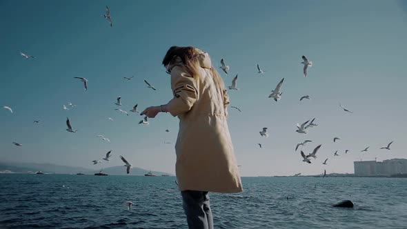 Girl by the ocean with a huge flock of birds around her