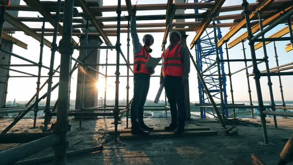 Scaffolding and Two Engineers Talking at the Site