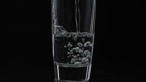 Pouring Up Shot of Vodka Into Drinking Glass. Slow Motion. Black Background