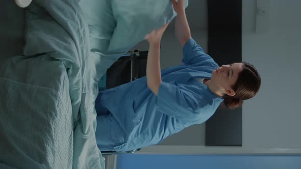 Vertical Video Nurse Preparing Bed and Blanket in Hospital Ward