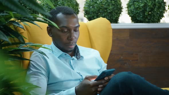 An African American Man Uses a Smartphone To Communicate on the Internet.