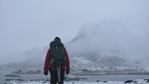 Hiker Walking Through Snow Towards Fjord