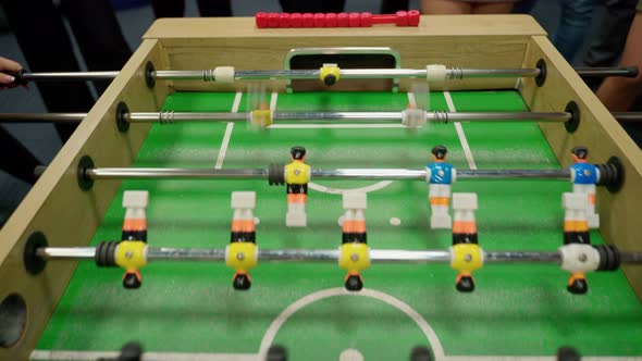 Unrecognizable people emotional play table football soccer closeup 4K. IT workers team resting