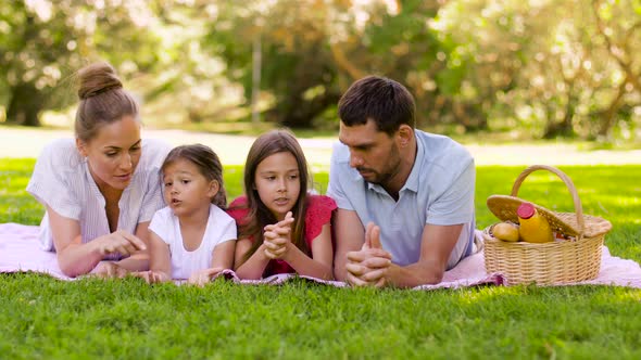 Family Lying on Picnic Blanket in Summer Park