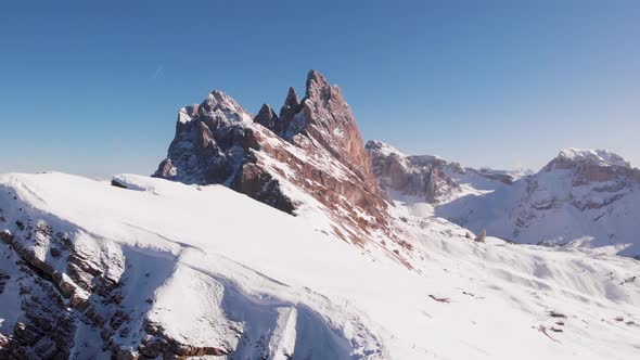 Dolomites mountain peak covered in snow on a sunny day, aerial paning