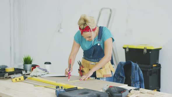 Woman Drawing Line on Plywood in Workshop