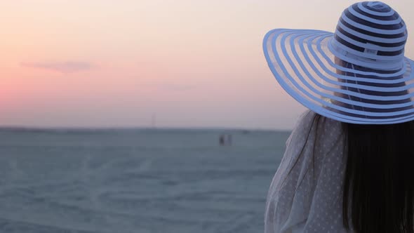 Elegant Woman with Glass of Wine Resting on Beach at Sunset