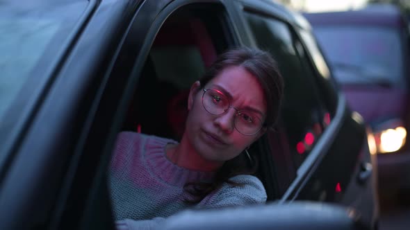 young woman looking through a car window in a night traffic jam