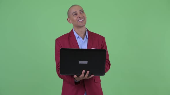 Happy Bald Multi Ethnic Businessman Thinking While Using Laptop