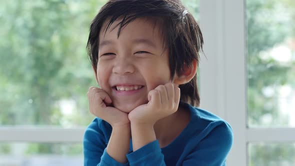 Cute Asian Child Resting Chins On Hands On Wood Table