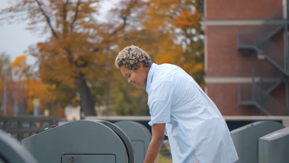 Young Afro Woman Throwing Plastic Bottle in Trash Bin Outdoors,