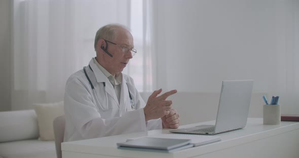 Elderly Experienced Male Professor of Medicine Is Lecturing Online Sitting at Office, Teaching