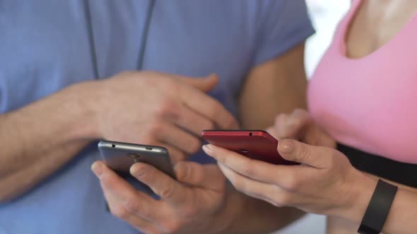 Female and Her Personal Trainer Synchronizing Cellphones Before Starting Workout