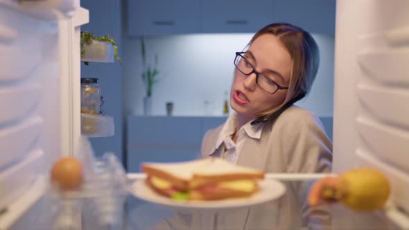 Busy business woman talking on phone and taking plate with sandwich