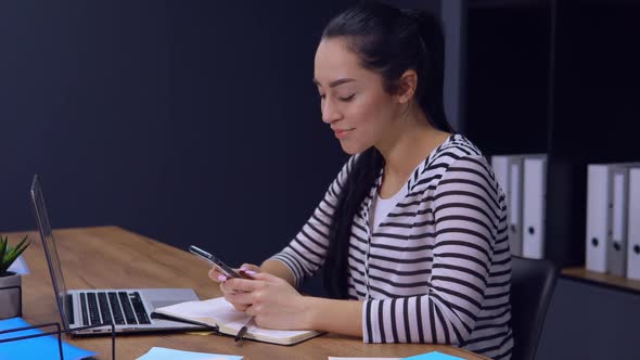 Businesswoman Typing Message on Mobile at Work