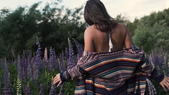 Young Woman in Purple Flower Field Enjoying Nature. Back View of a Girl, She Walks in Wildflowers