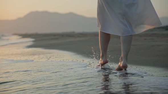 Young woman walking on the waves on the beach in summer