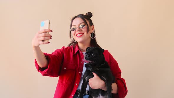 Stylish trendy woman makes a selfie online life stream video call chat on mobile phone with her pet