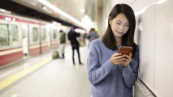 Woman using cellphone and standing at subway station